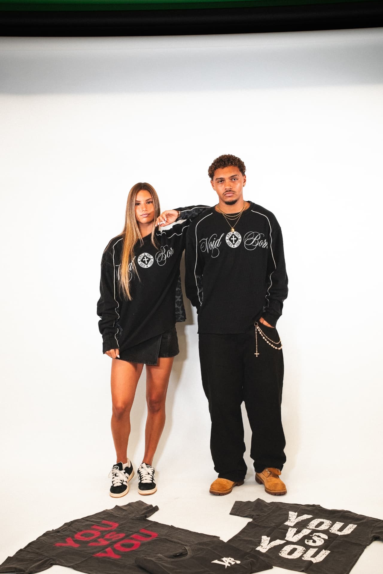 Two models in Voidborn black Void Born sweatshirts with You Vs You tees on the studio floor